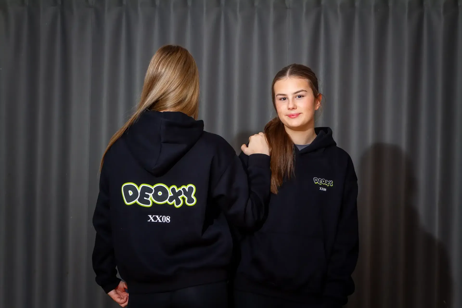 A woman in a black hoodie is holding a basketball on a basketball court.