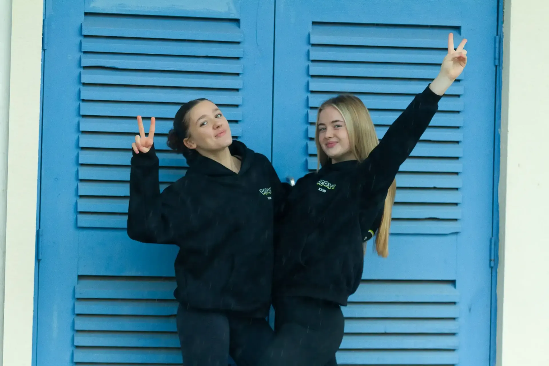 Two girls are posing for a picture in front of a blue door.