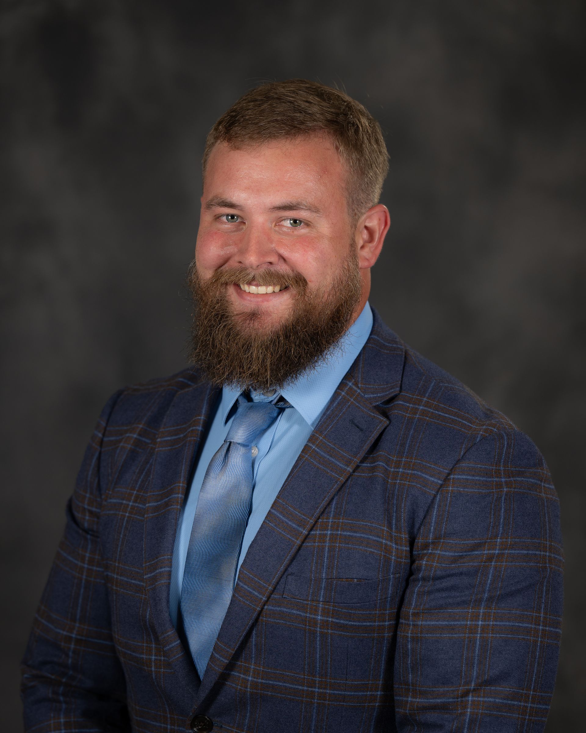 A man with a beard is wearing a suit and tie.