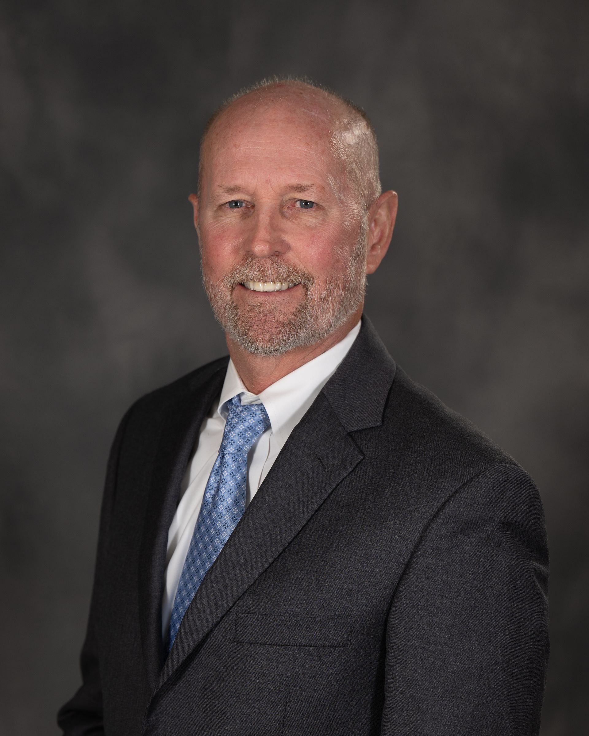 A man in a suit and tie is smiling for the camera.