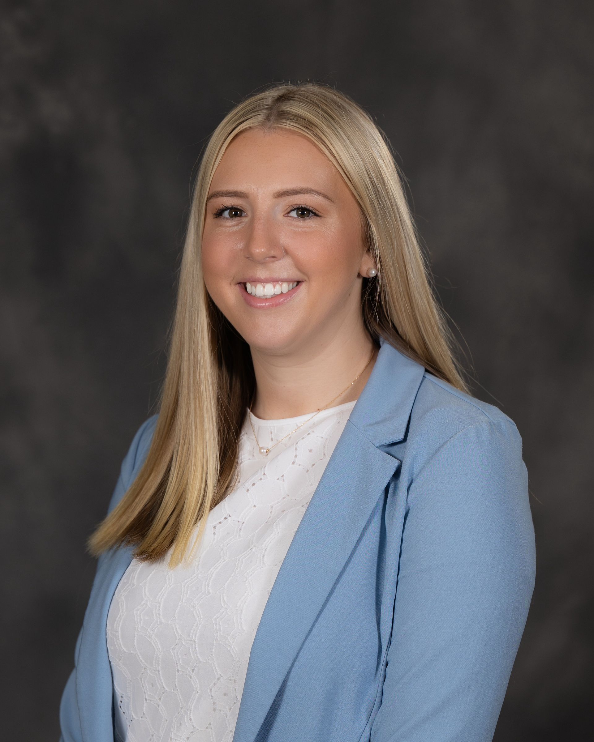 A woman is wearing a blue jacket and a white turtleneck.
