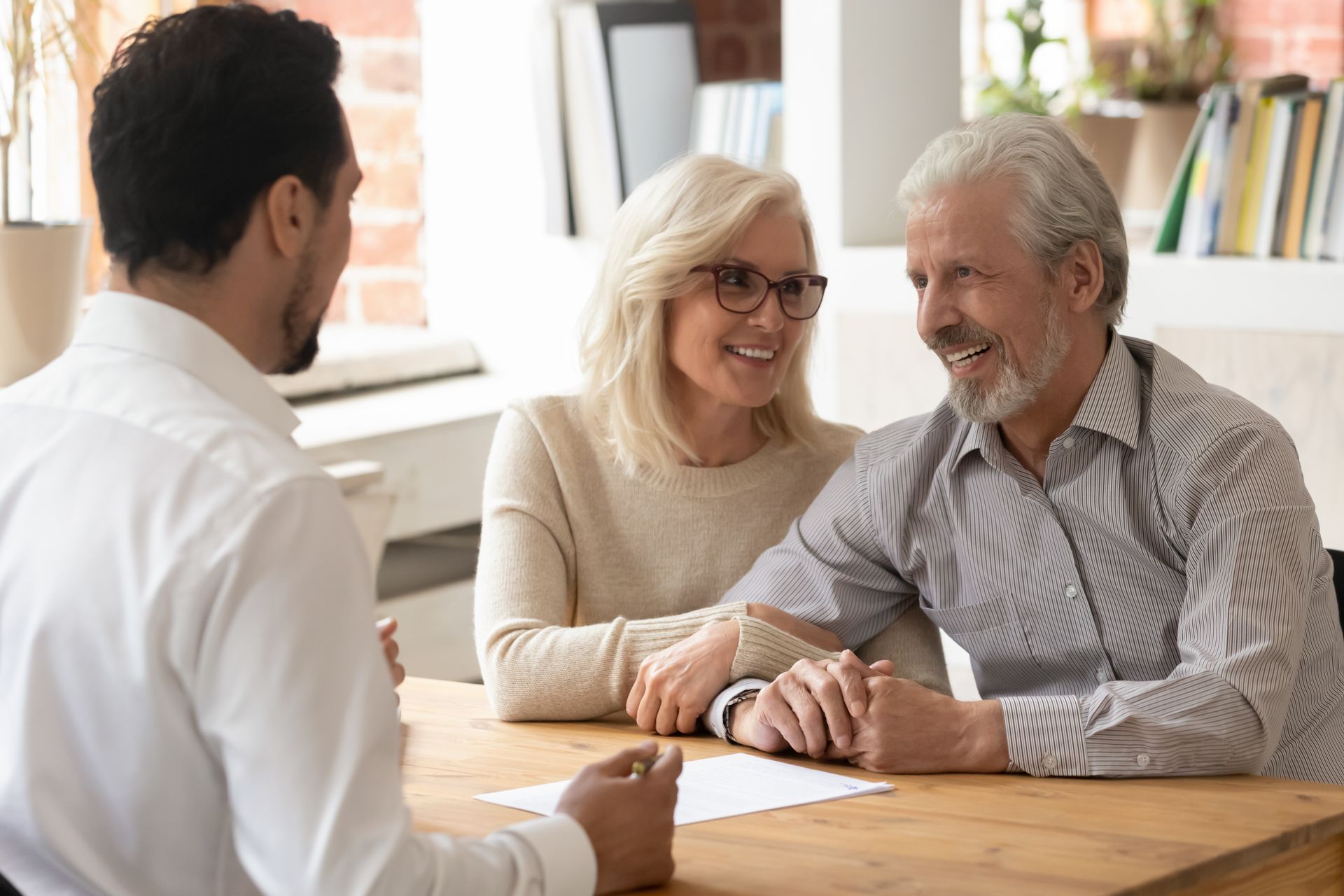 An older couple is sitting at a table talking to a man.