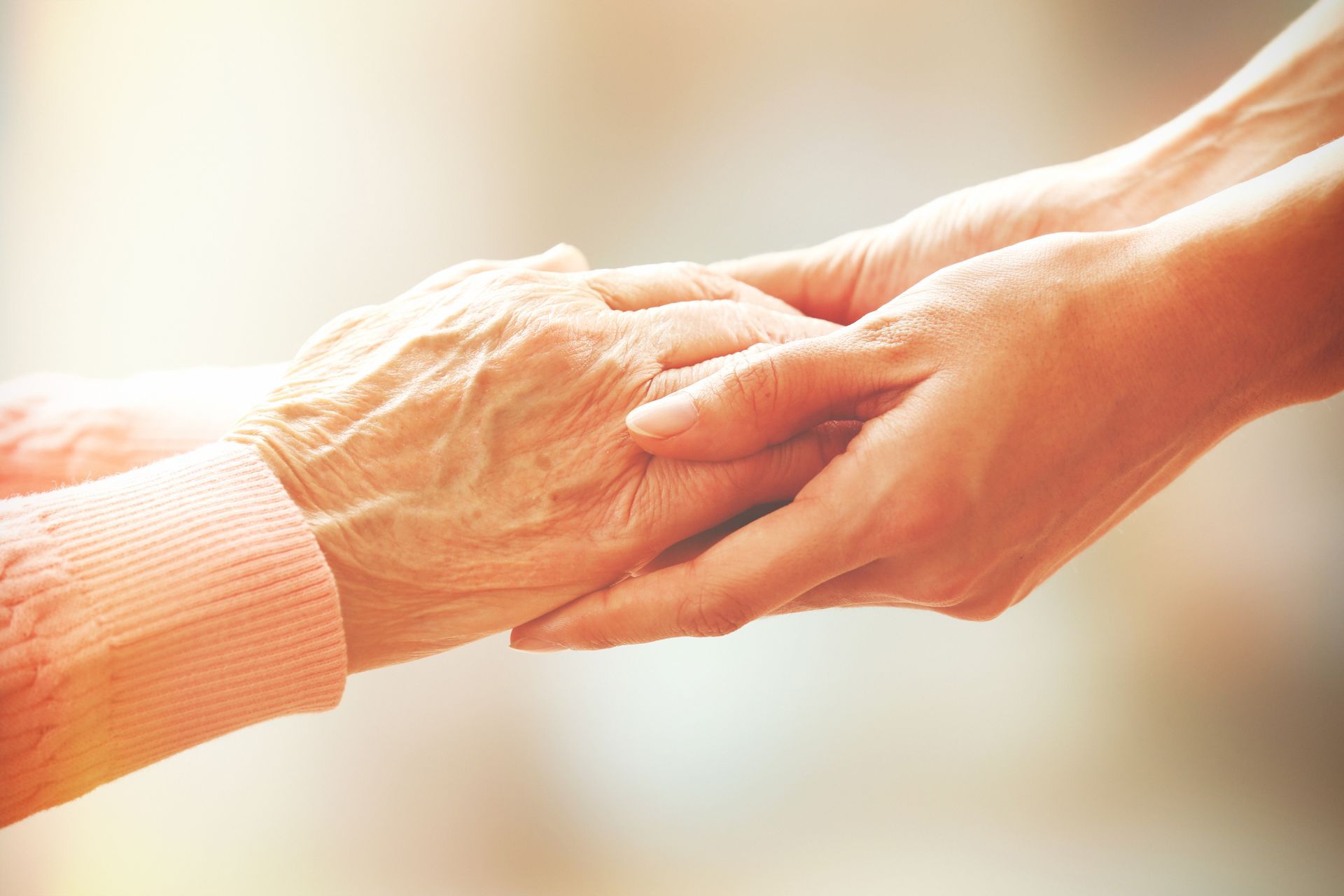 A woman is holding the hand of an older woman.