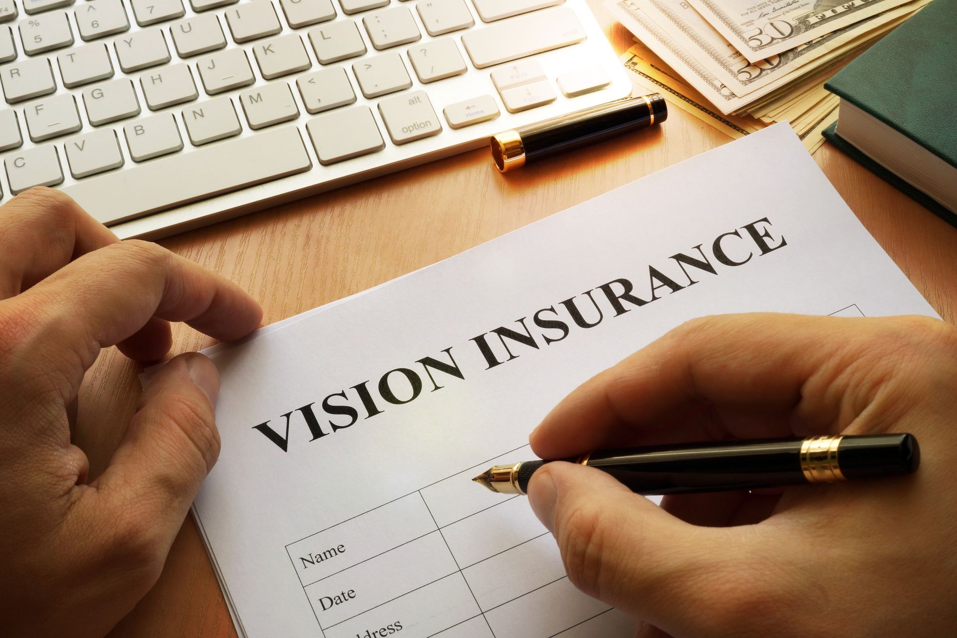 A person is filling out a vision insurance form with a pen