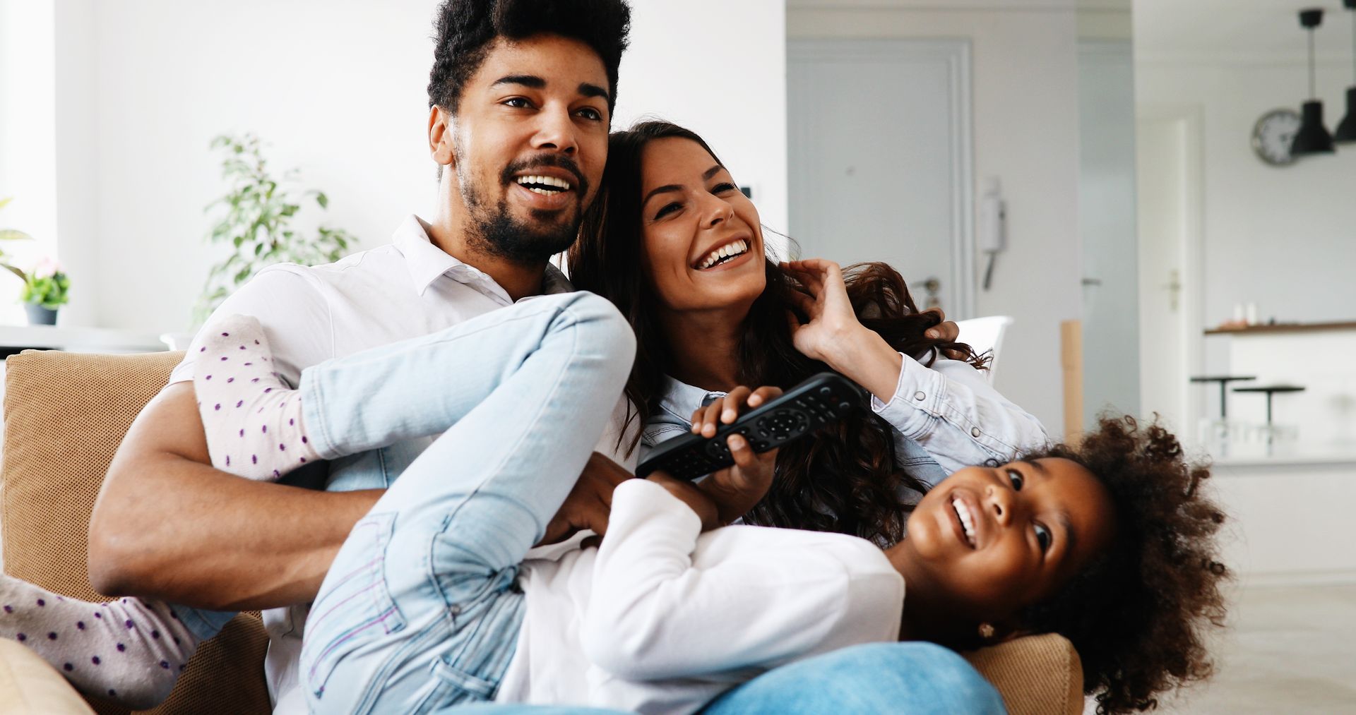 A family is sitting on a couch watching tv together.