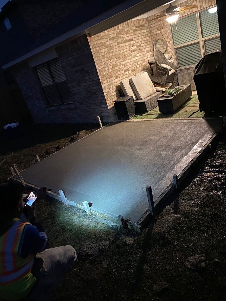 A man is working on a concrete patio at night.