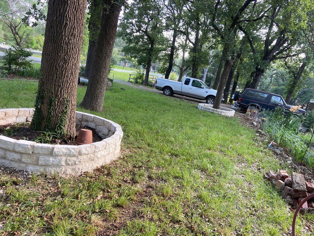 A white truck is parked in the grass next to a tree.