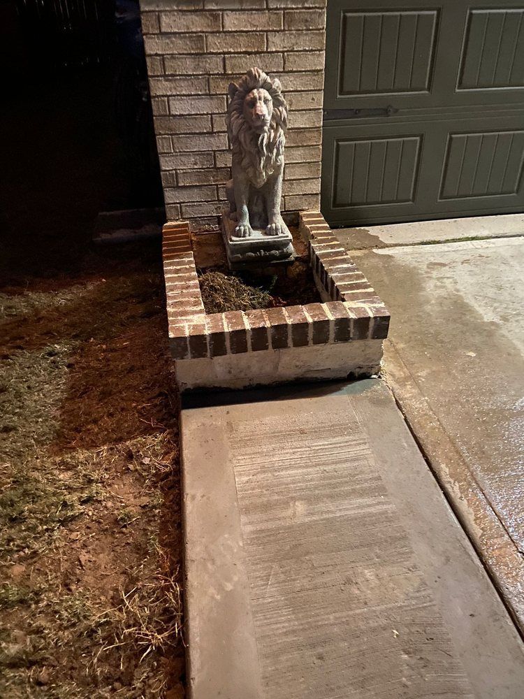 A statue of a lion is sitting in a planter next to a brick wall.