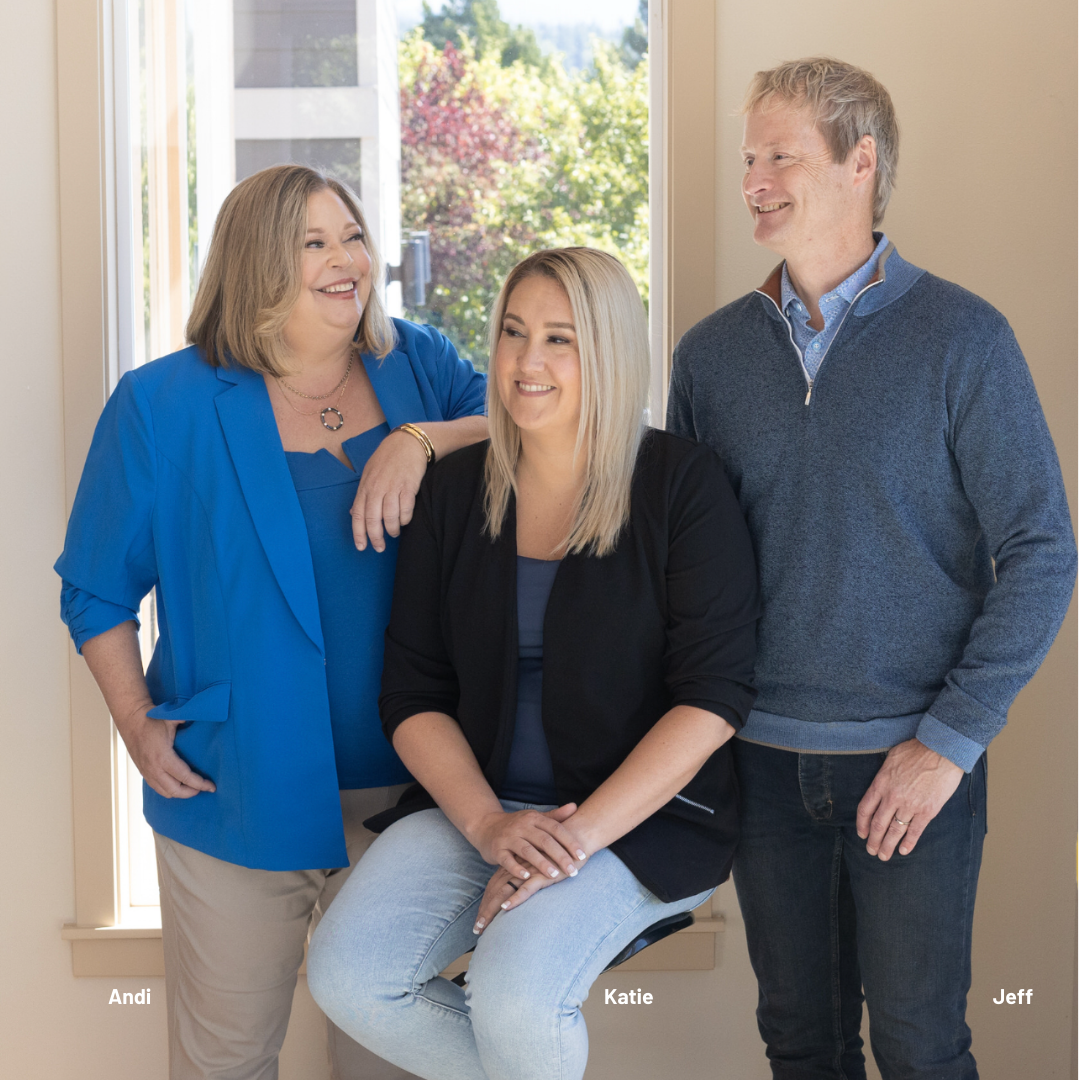 A family is sitting on the floor in a living room holding a cardboard house.