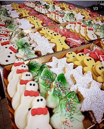 Un vassoio di vari biscotti natalizi colorati: pupazzi di neve, alberi, stelle, omini di pan di zenzero, decorati con glassa e granelli.