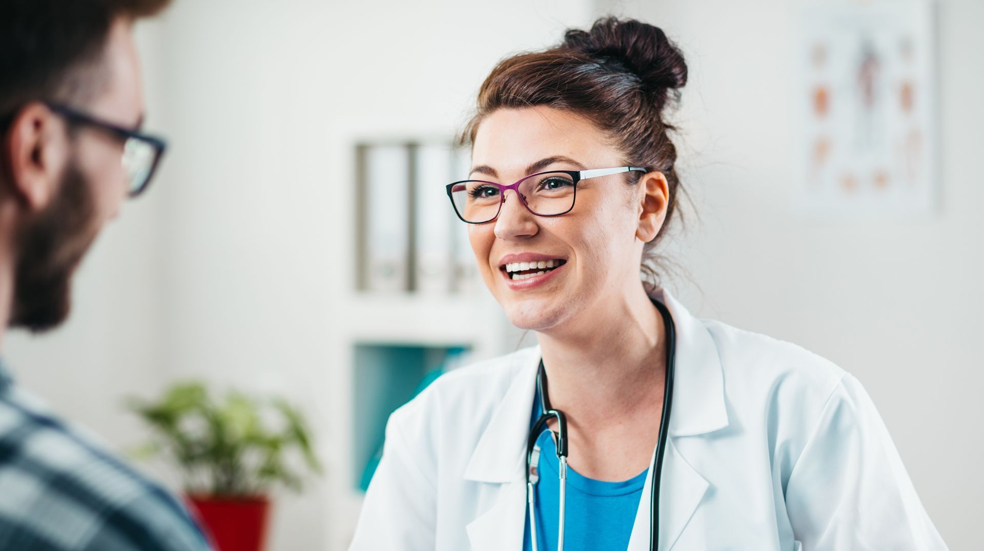 A doctor is smiling while talking to a patient in a hospital.