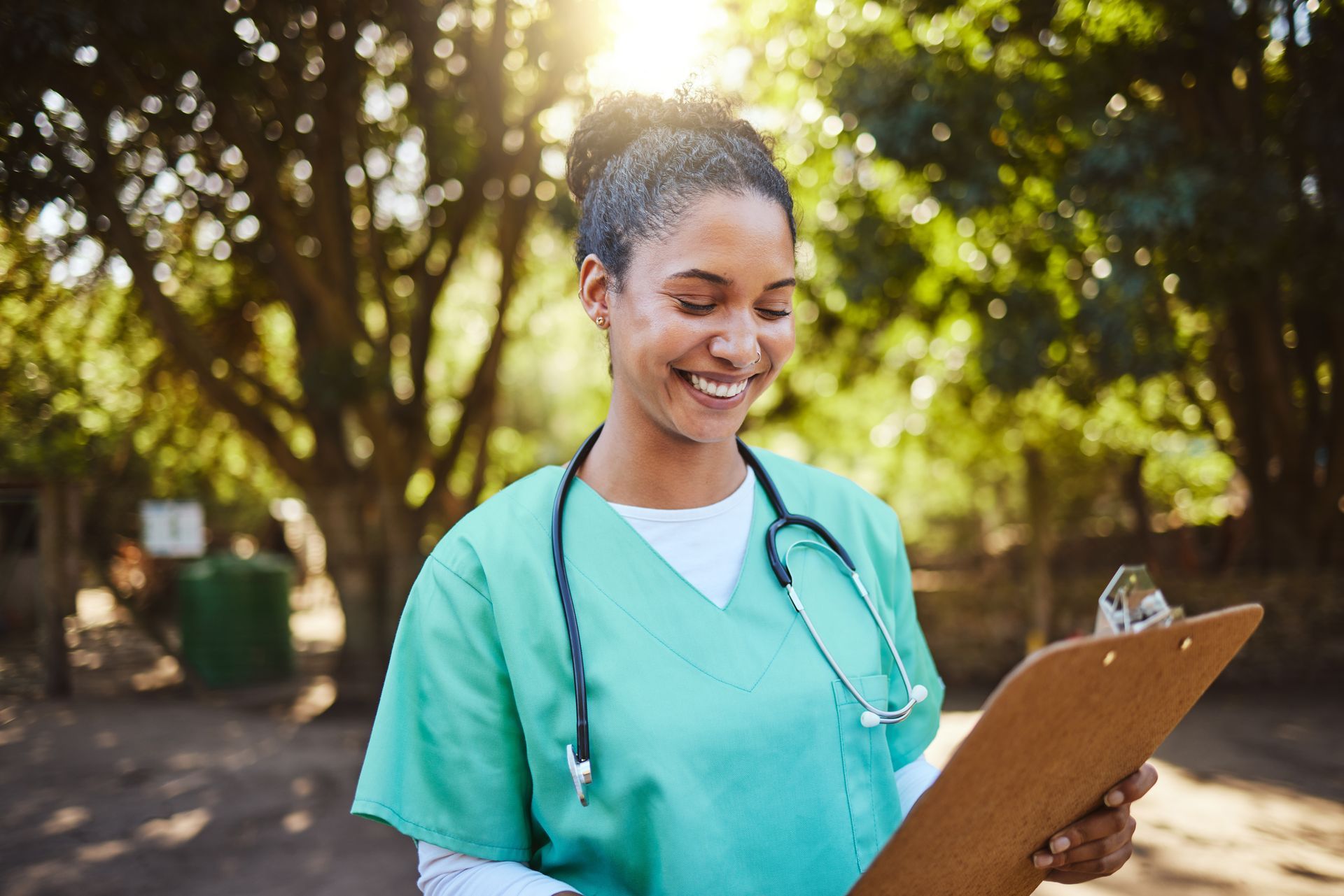 A nurse is smiling while looking at a clipboard.