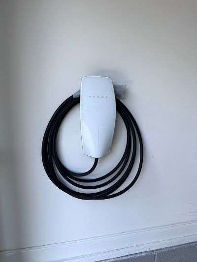 A tesla charging station is hanging on a white wall.