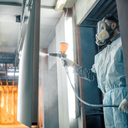 Factory worker applying a powder coat to stainless steel