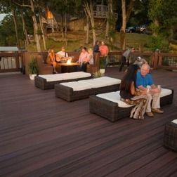 Outdoor deck with several lounge chairs, some people, and a small fire pit.