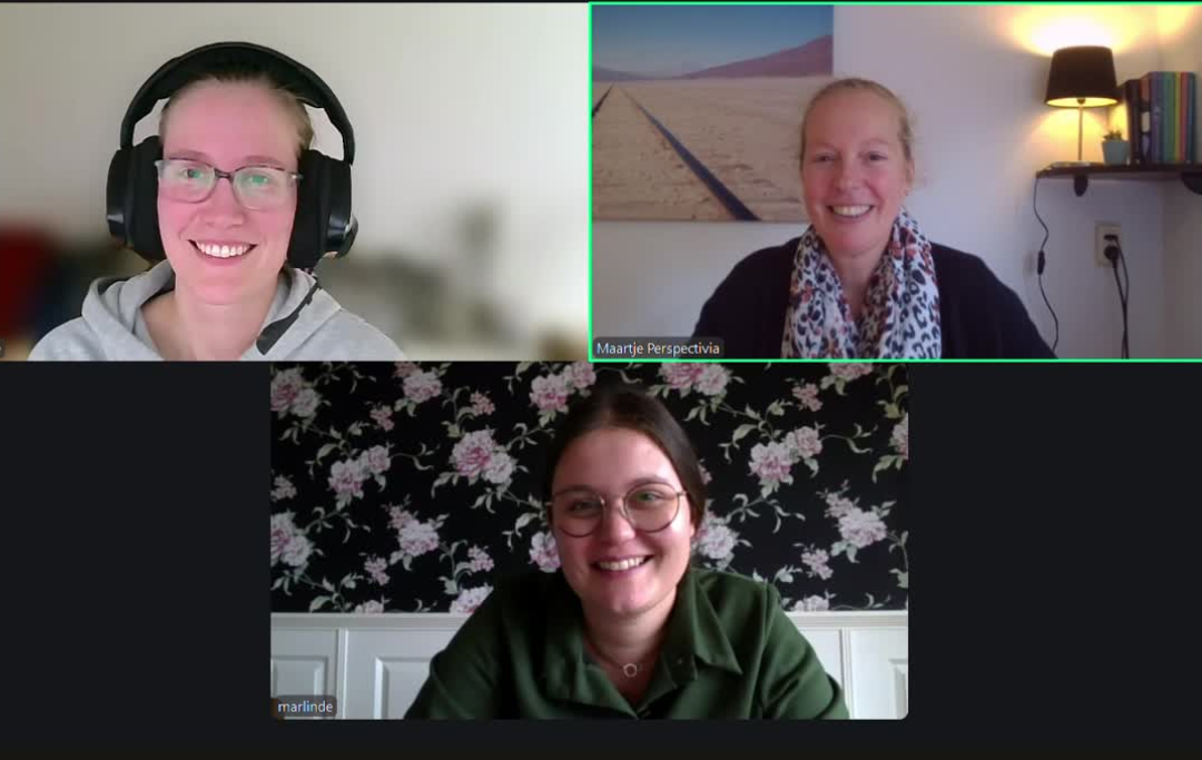 Een videogesprek met drie deelnemers, waarop drie lachende mensen te zien zijn in hun respectievelijke thuiswerkplekken.