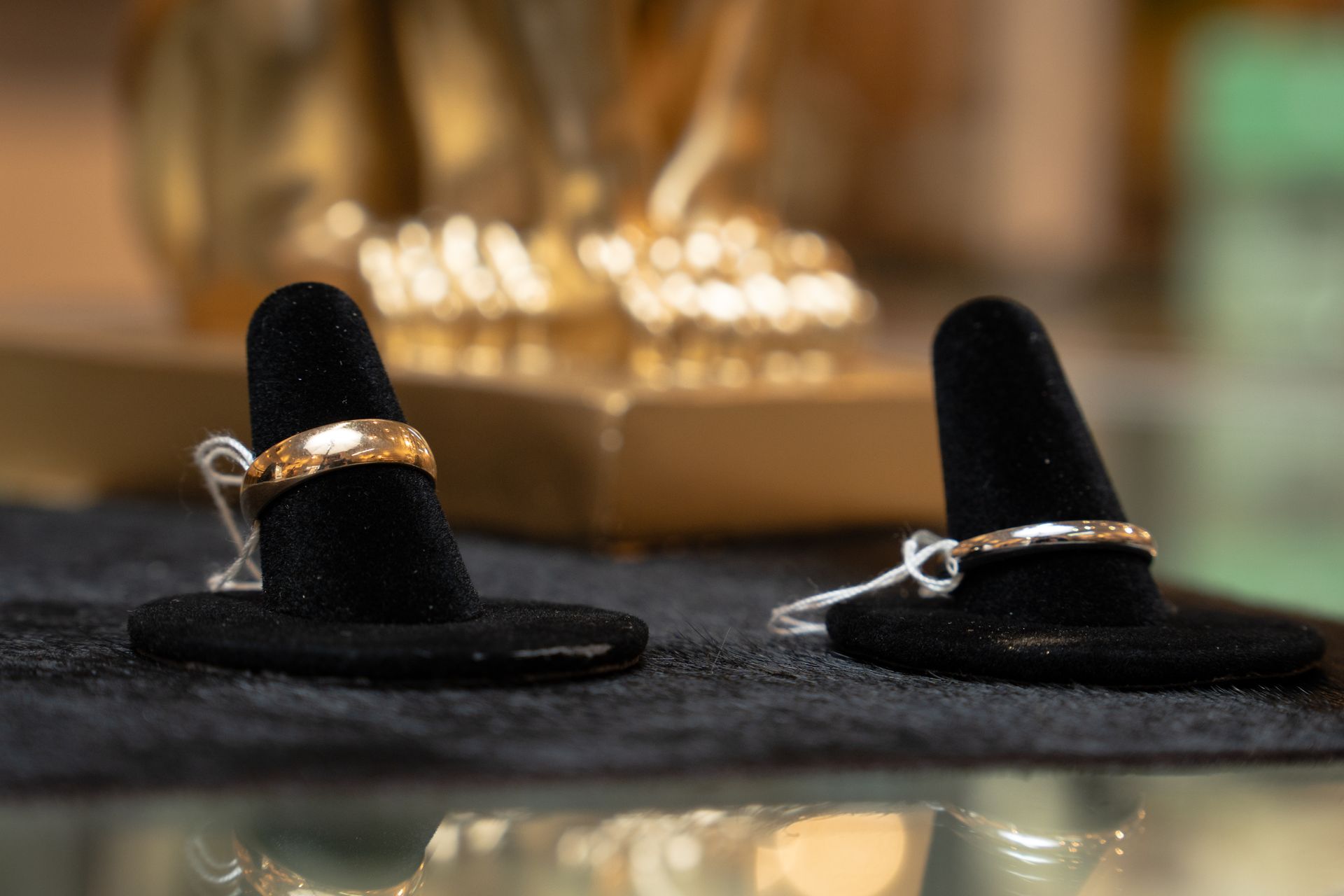 Two rings on black velvet ring displays, in front of a golden statue.