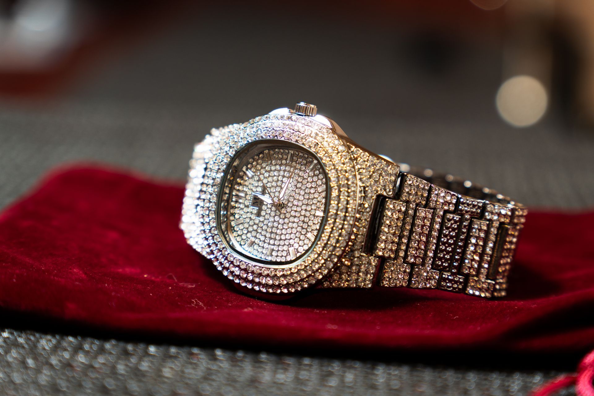 Diamond-encrusted wristwatch on a red velvet pouch.