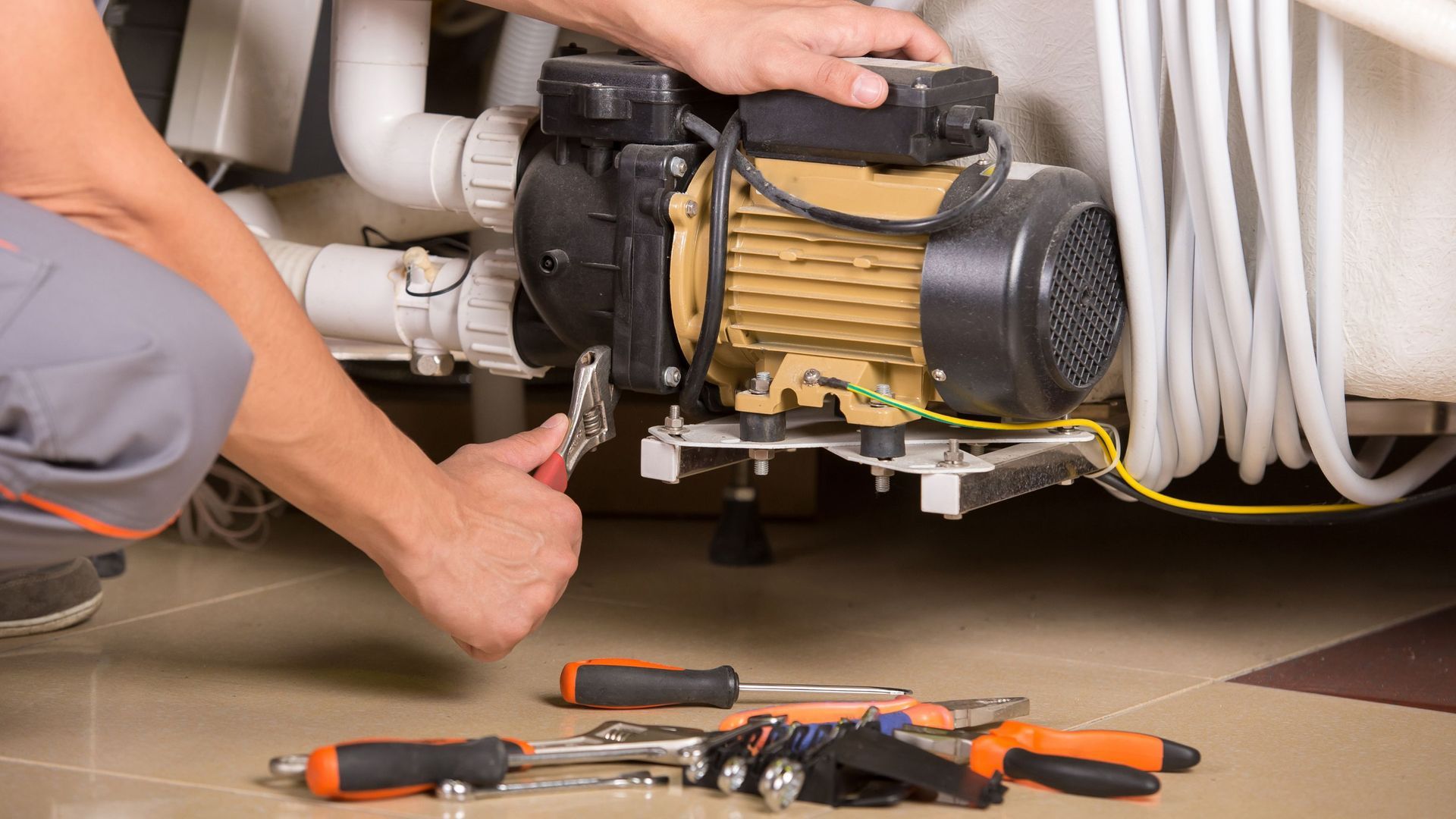 A man is fixing a water pump in a bathroom.