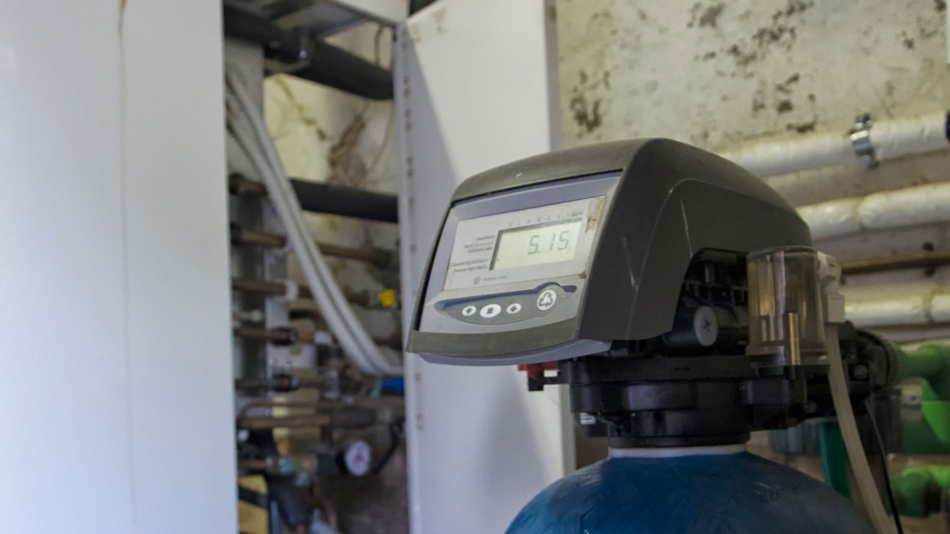 A water filter is sitting in a room next to a wall.