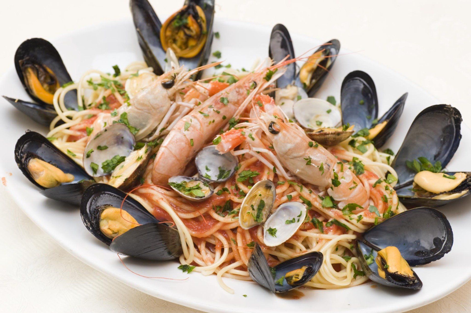 Un piatto bianco condito con pesce fritto, gamberi, calamari e fette di limone.