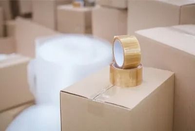Two rolls of tape are sitting on top of a cardboard box.
