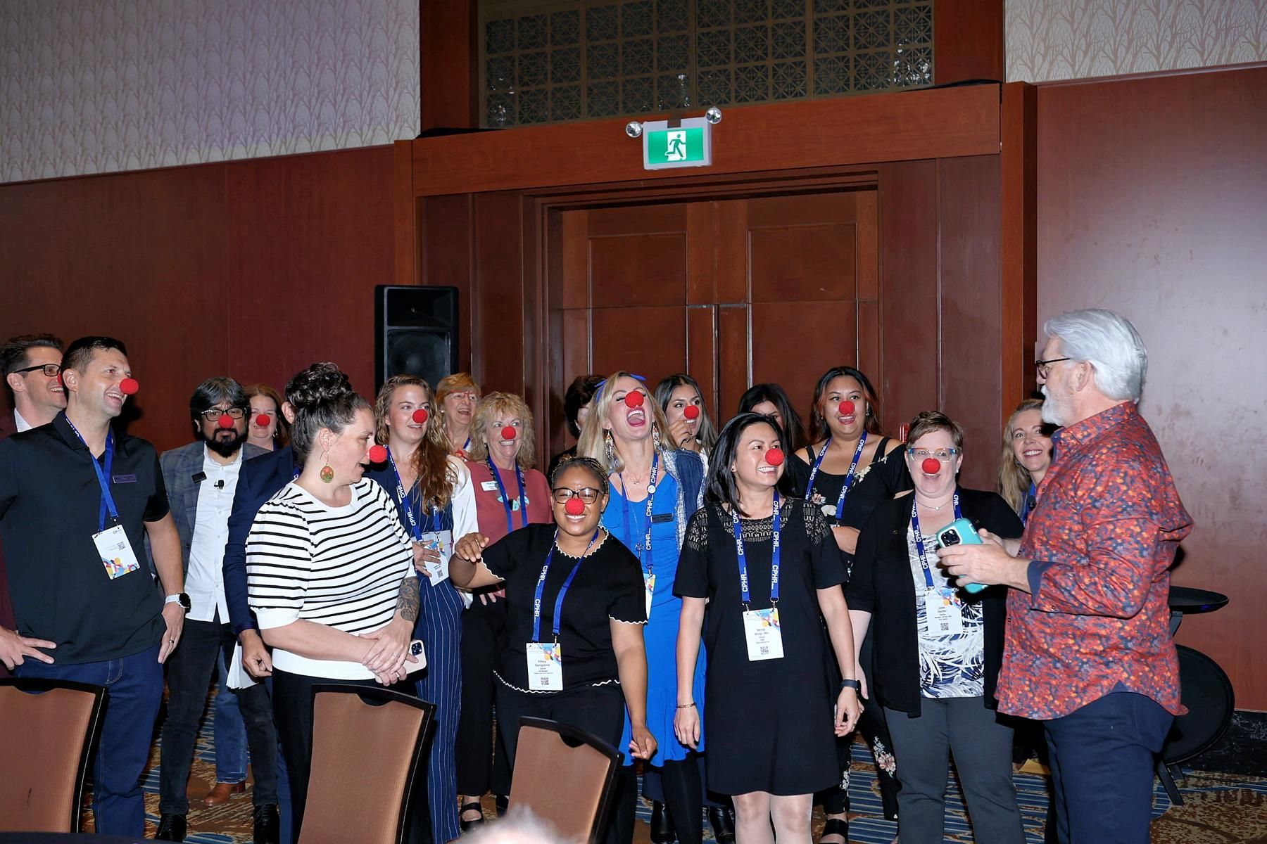 A group of people wearing red noses are standing in a room.