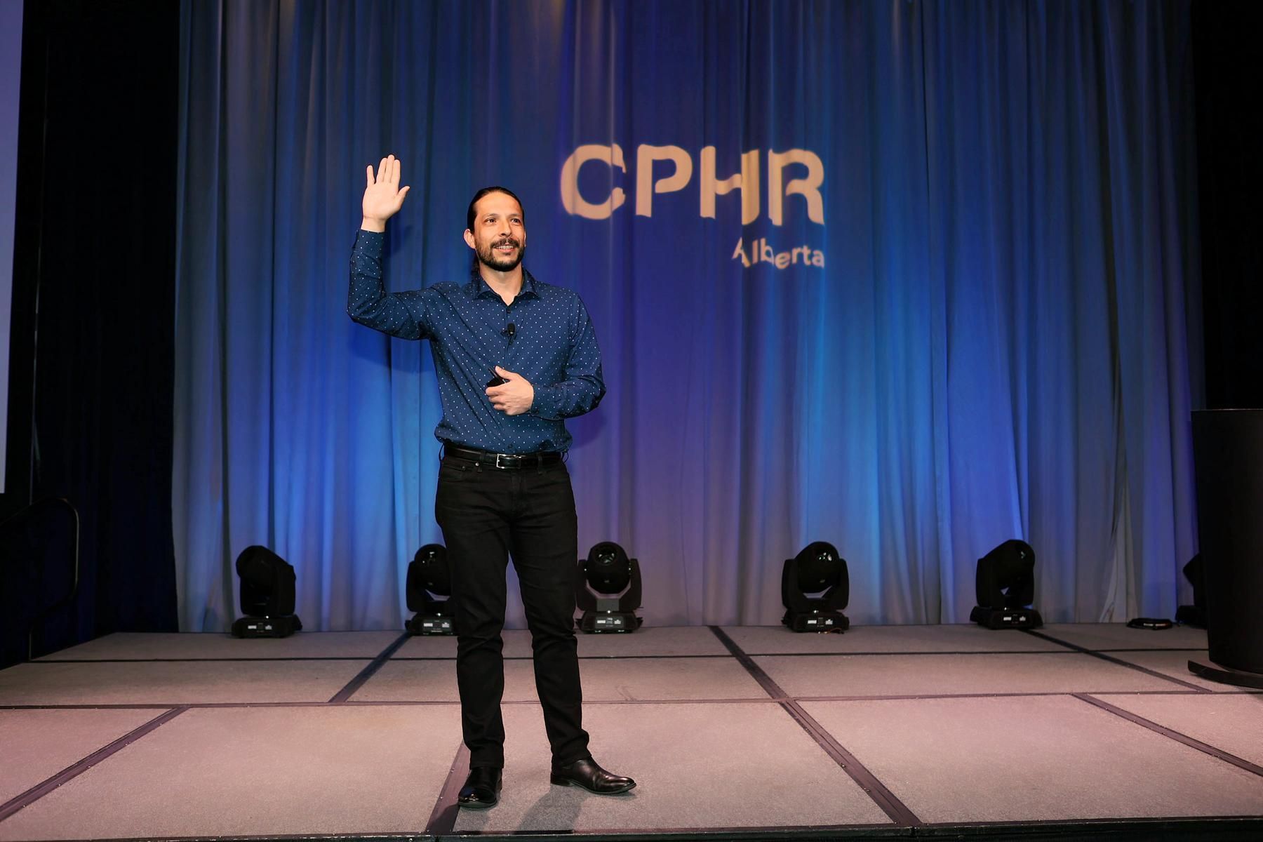 A man is standing on a stage in front of a cphr logo.