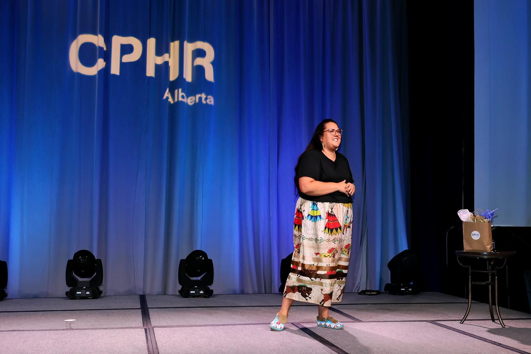 A woman is standing on a stage in front of a cphr sign.