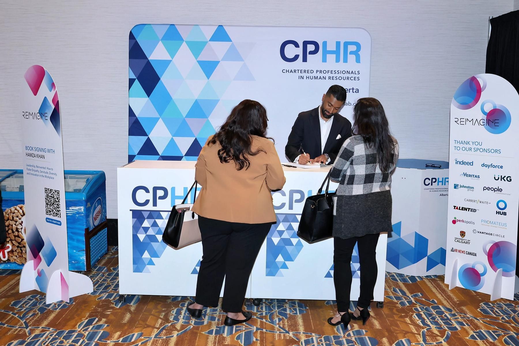 A man is talking to two women at a cphr booth.