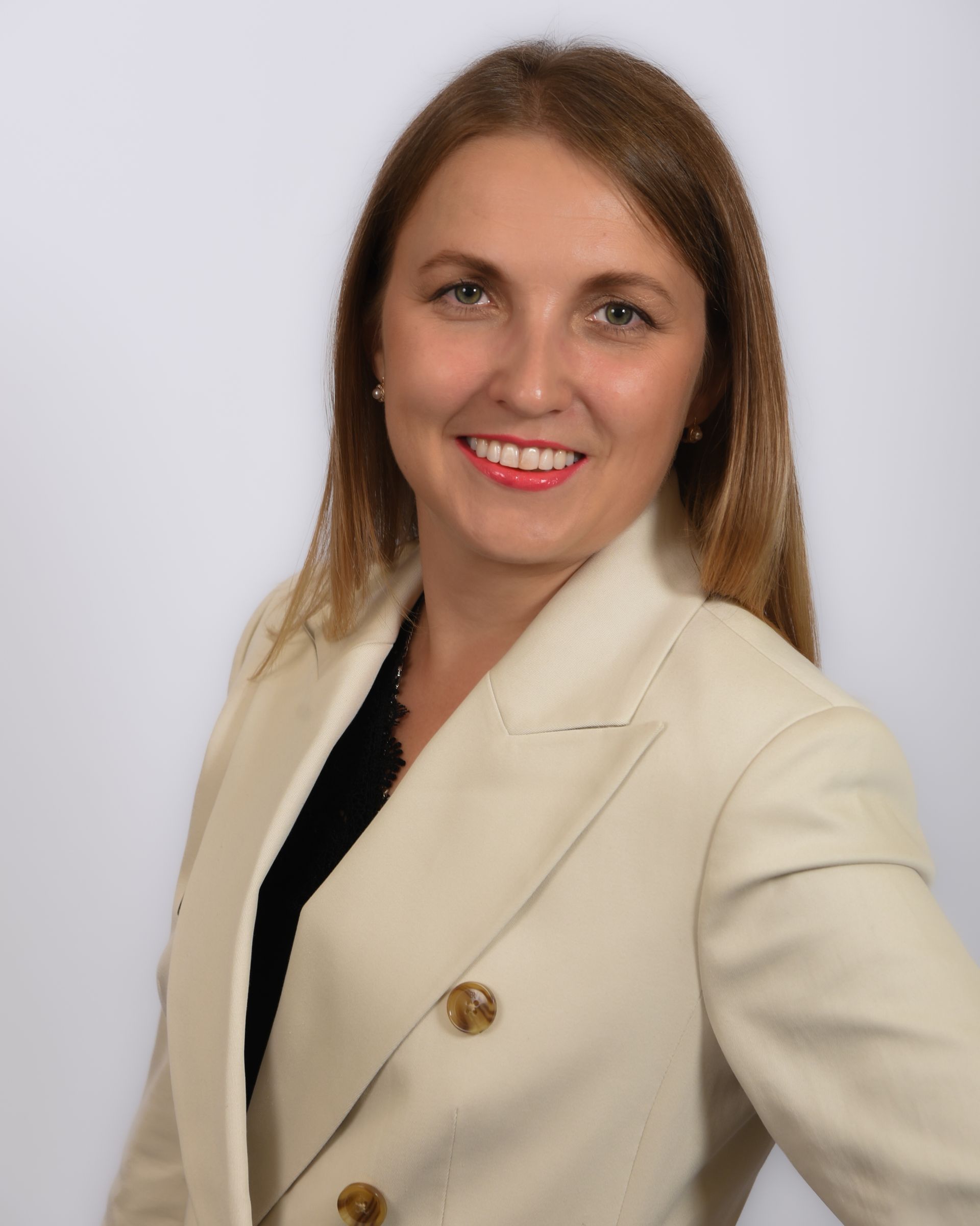 A woman in a white jacket is smiling for the camera.