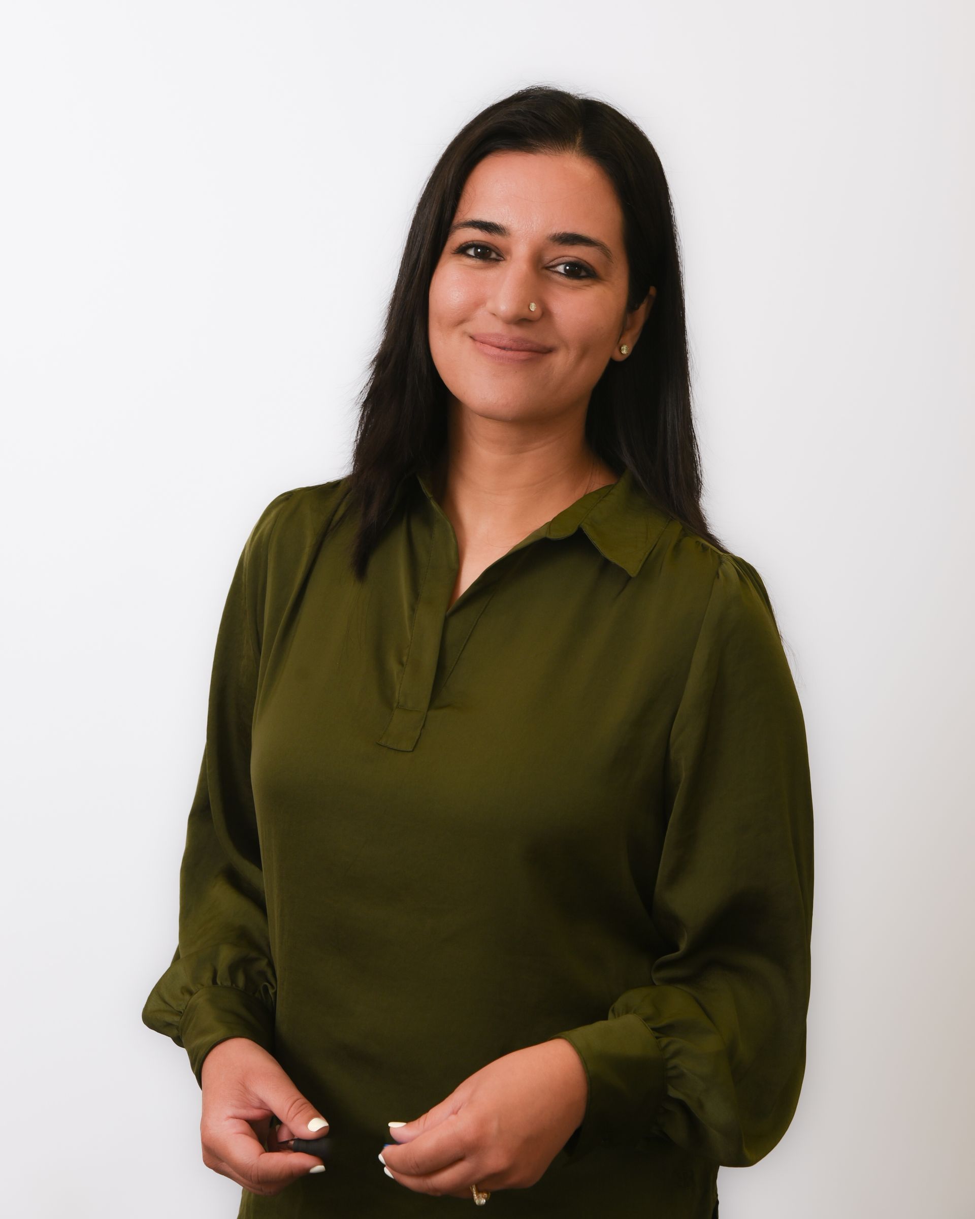 A woman in a green shirt is standing in front of a white wall.