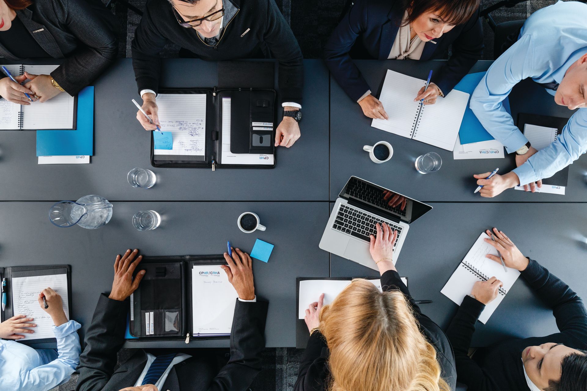 Man giving a presentation to a group in a brightly lit room. A screen shows the number 01.