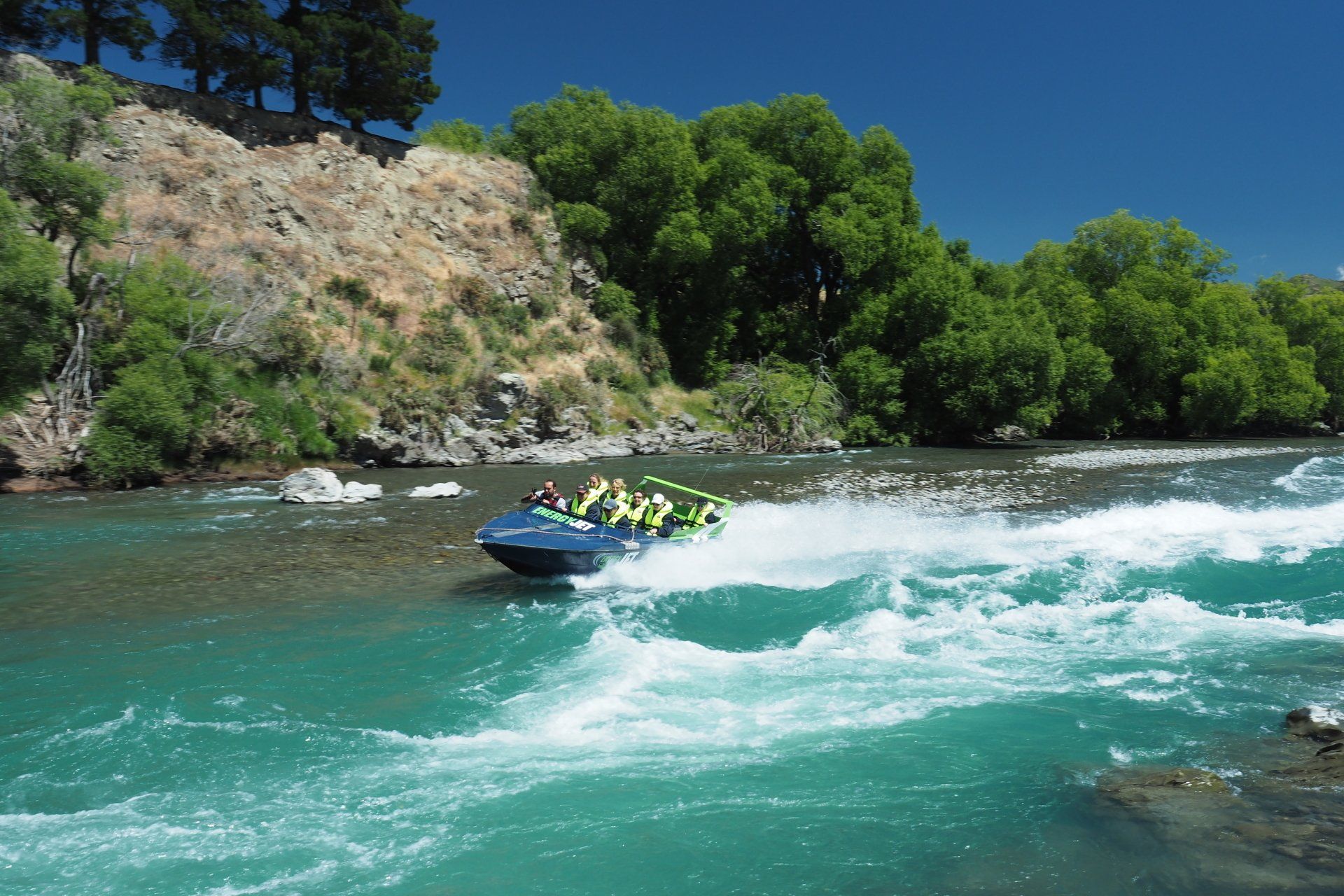 A group of people are riding a speedboat down a river