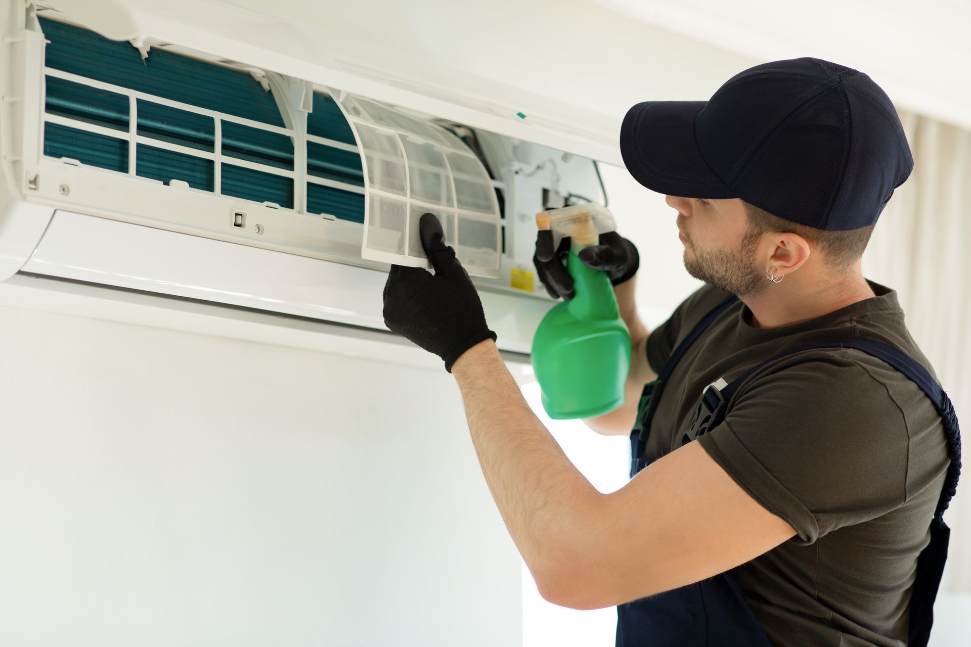 A technician cleaning an AC filter with a spray bottle.