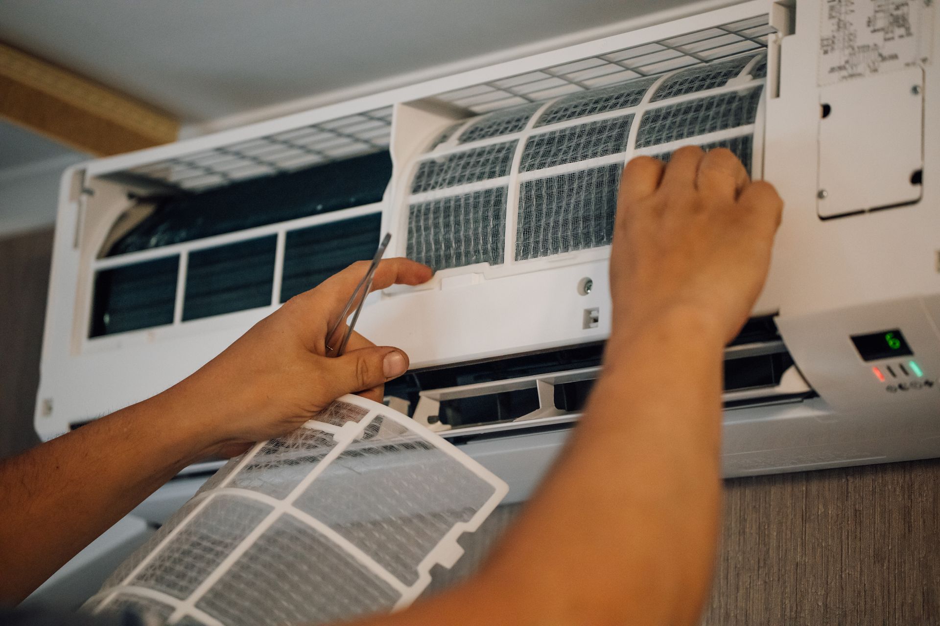 Person cleaning an air conditioner filter indoors.