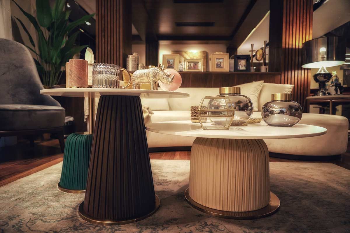 A living room with a couch , chairs , tables and vases