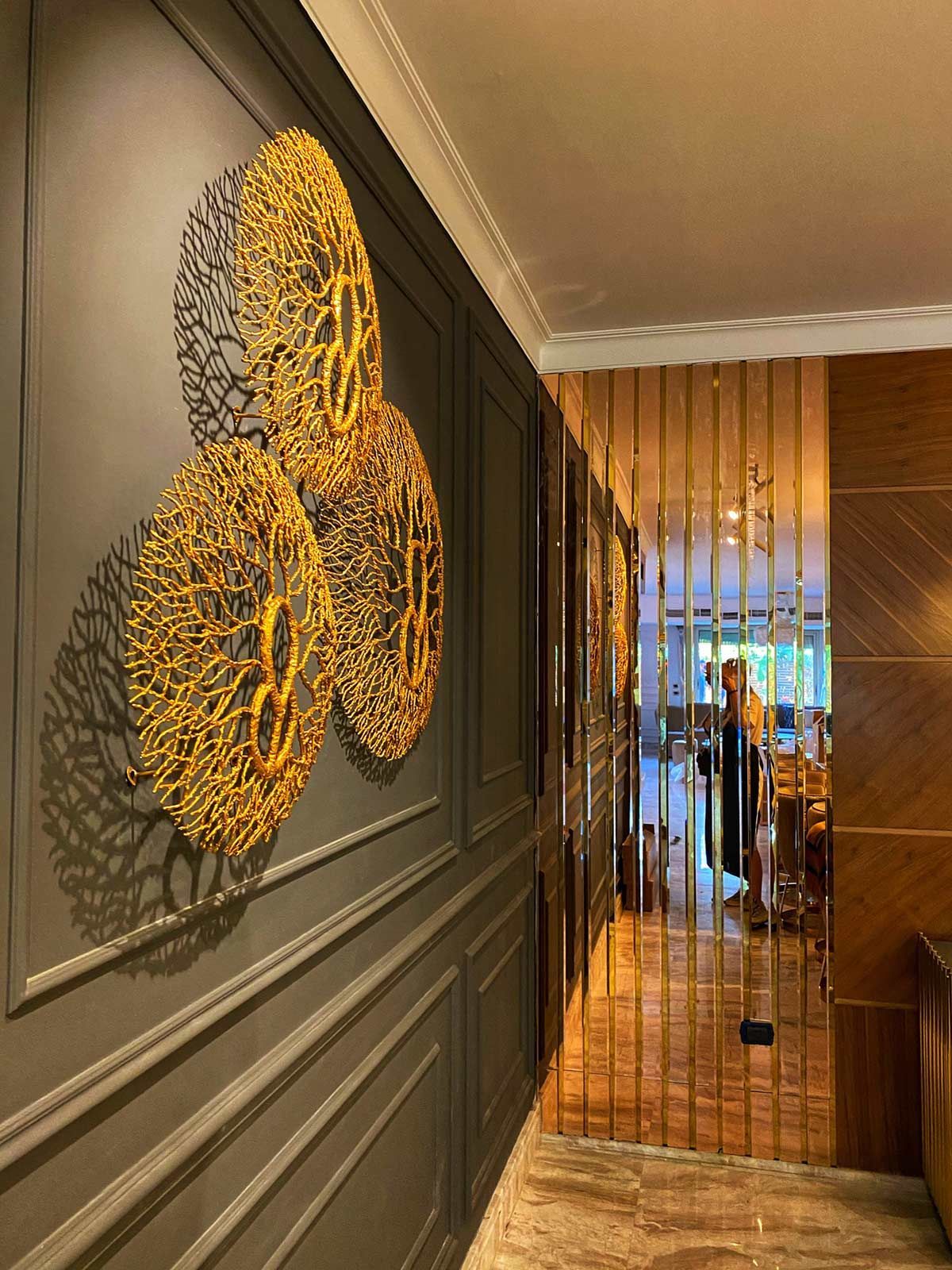 A hallway with a mirrored wall and a painting on the wall.