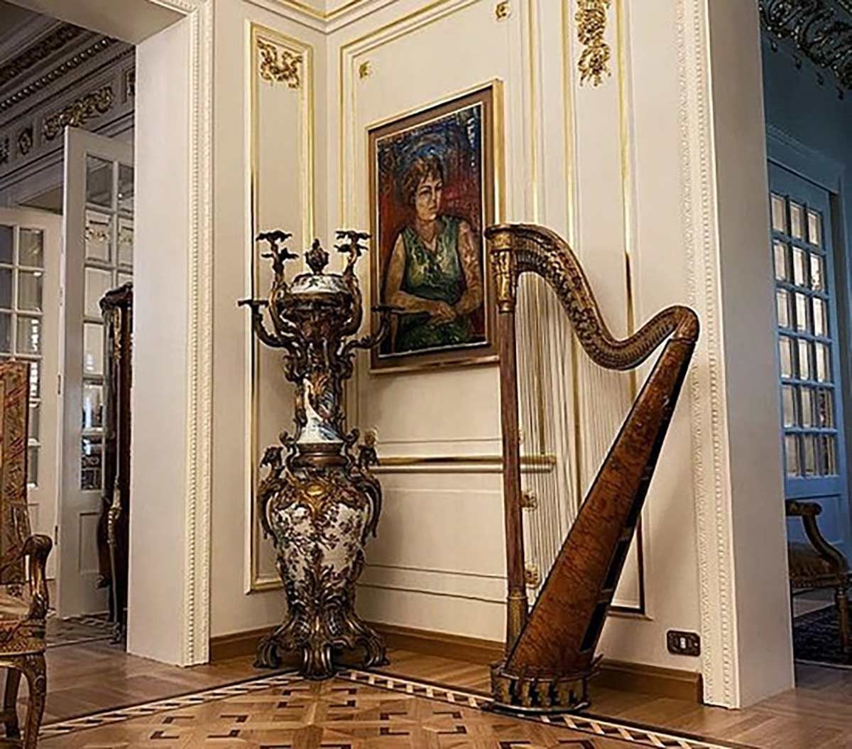 A harp is sitting next to a vase in a room with a painting on the wall.