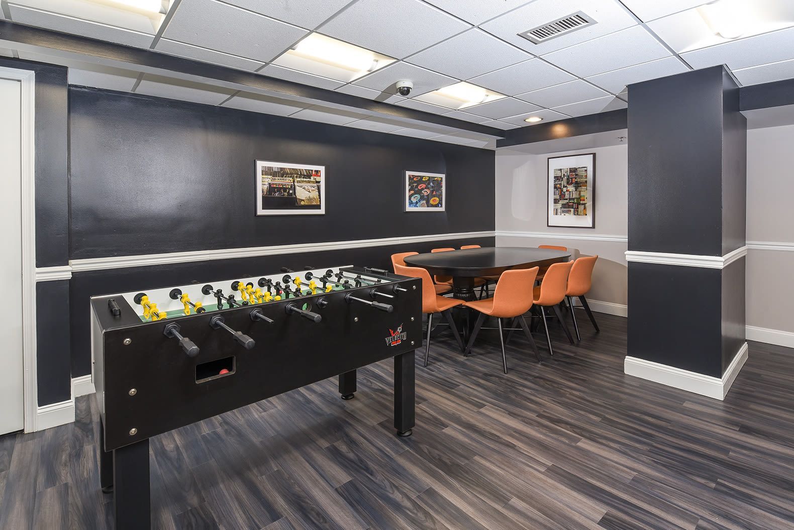 Game room with foosball table, dark walls, and orange chairs at Glenmont Station in Silver Spring, MD.