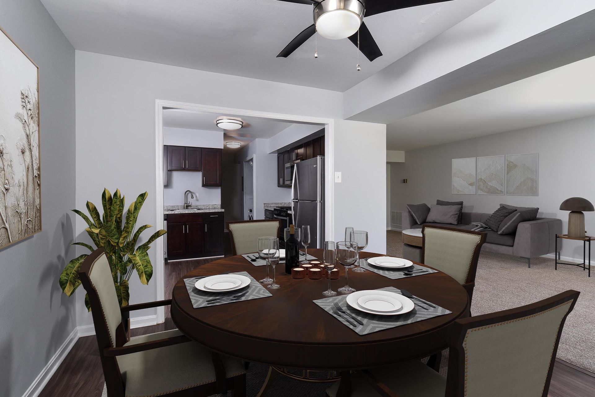 Dining room with round table, place settings, chairs, and view into kitchen and living room at Glenmont Station in Silver Spring, MD.