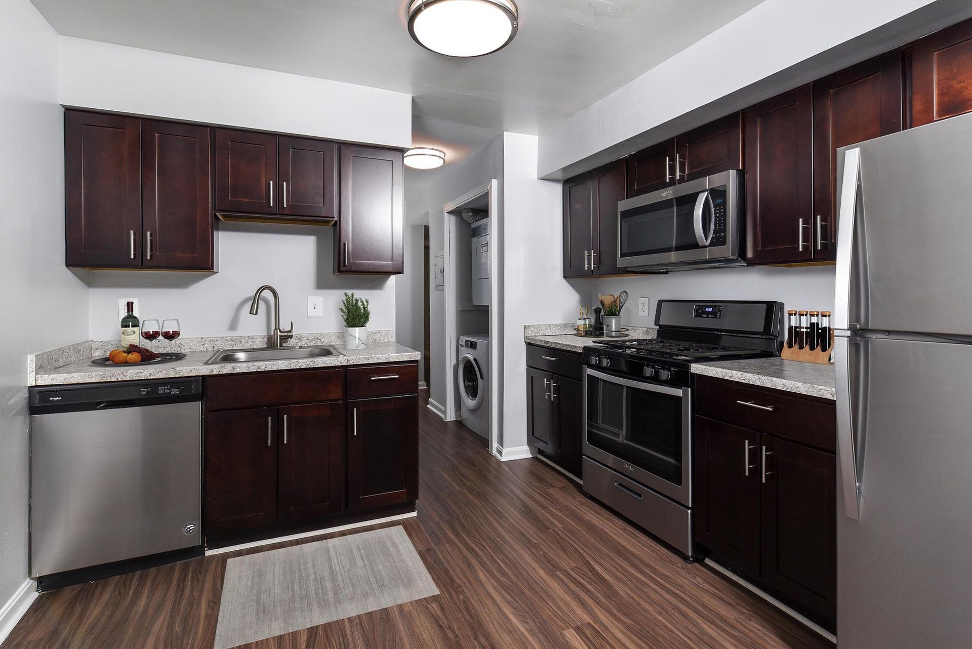 Kitchen with dark wood cabinets, stainless steel appliances, and gray countertops at Glenmont Station in Silver Spring, MD.
