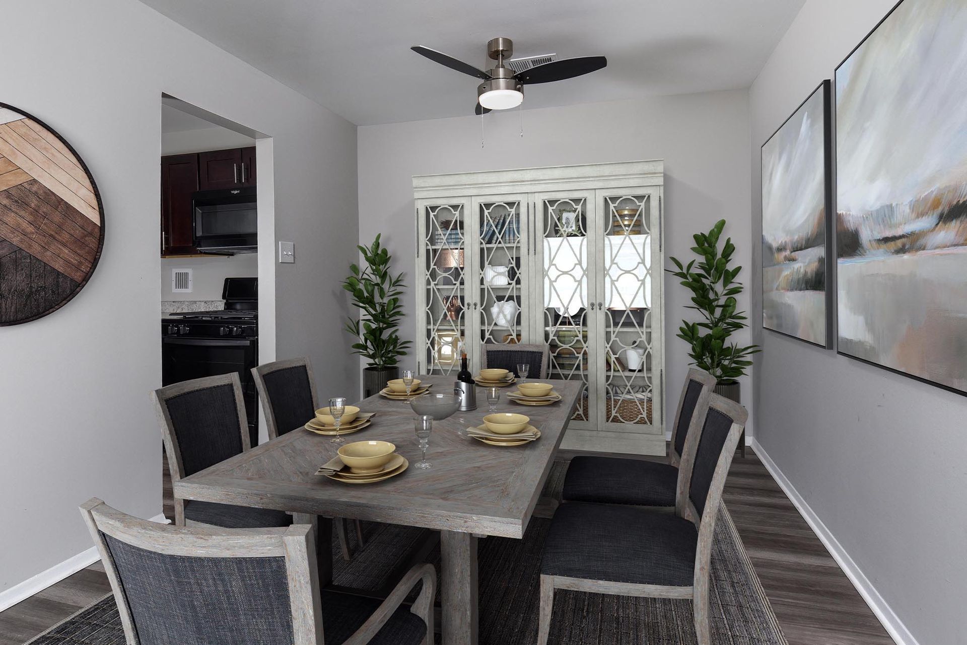Dining room with a table set for a meal, a hutch, and a doorway to a kitchen at Glenmont Station in Silver Spring, MD.