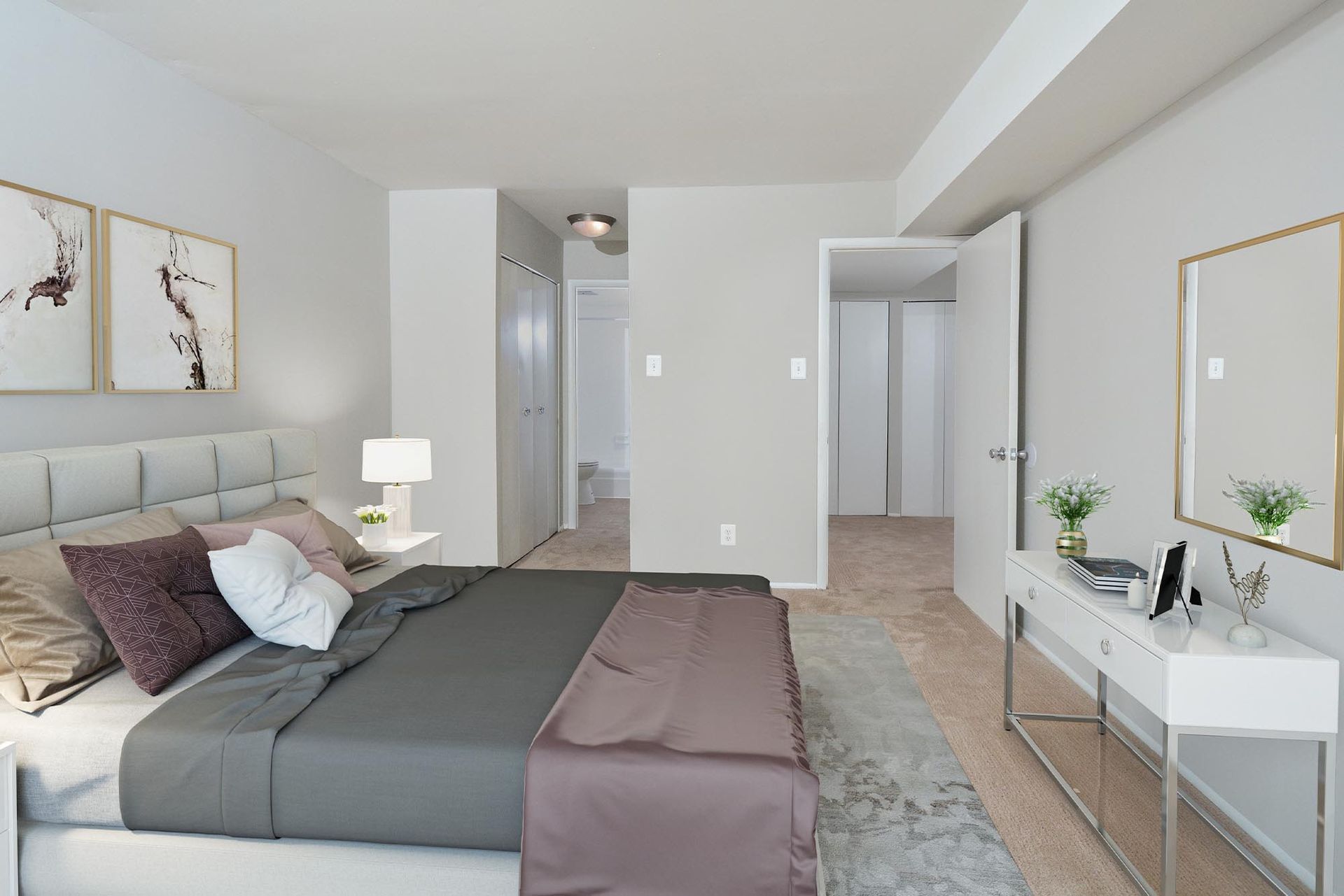 Bedroom interior with a bed, dresser, art, and doorway to another room. Neutral color palette at Glenmont Station in Silver Spring, MD.