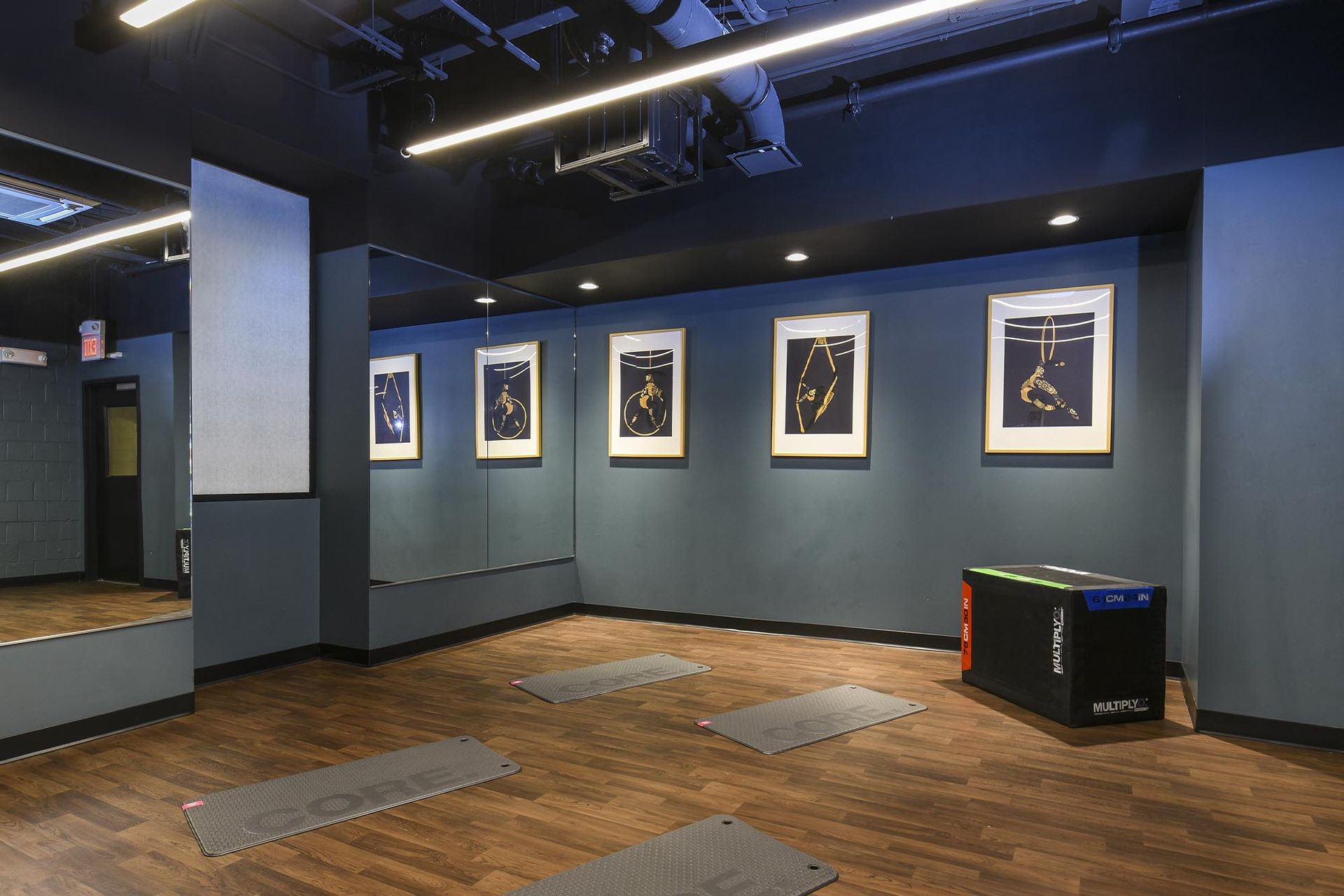 Yoga studio with framed art on teal wall, wood floor, and yoga mats at Glenmont Station in Silver Spring, MD.