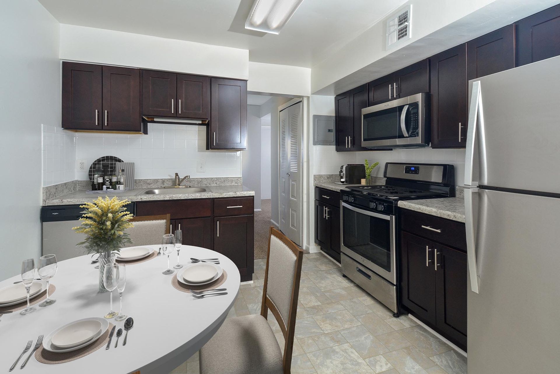 Kitchen with dark cabinets, stainless steel appliances, granite countertops, and a dining table at Glenmont Station in Silver Spring, MD.