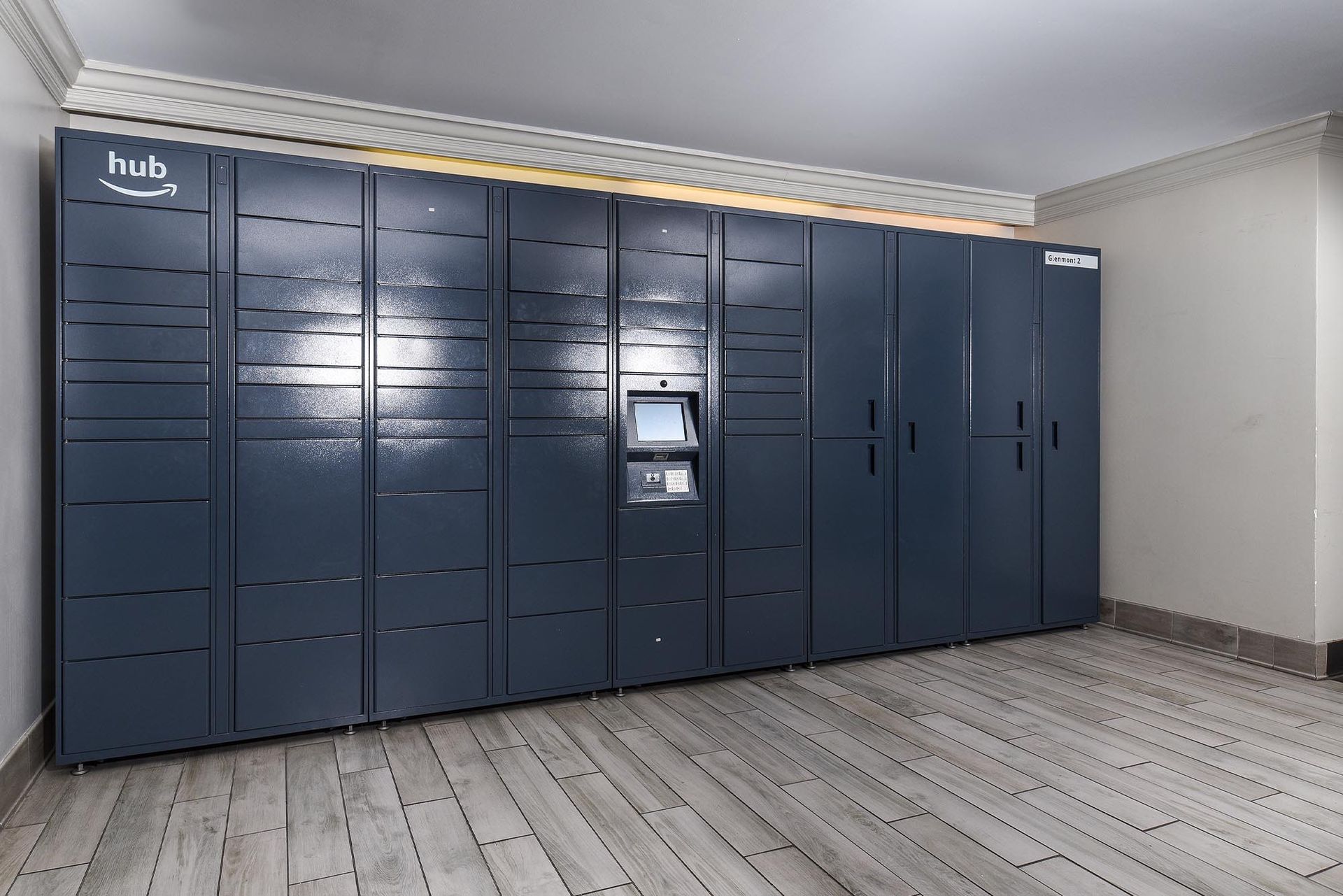 Dark blue Amazon Hub locker system in a room with light-colored flooring at Glenmont Station in Silver Spring, MD.