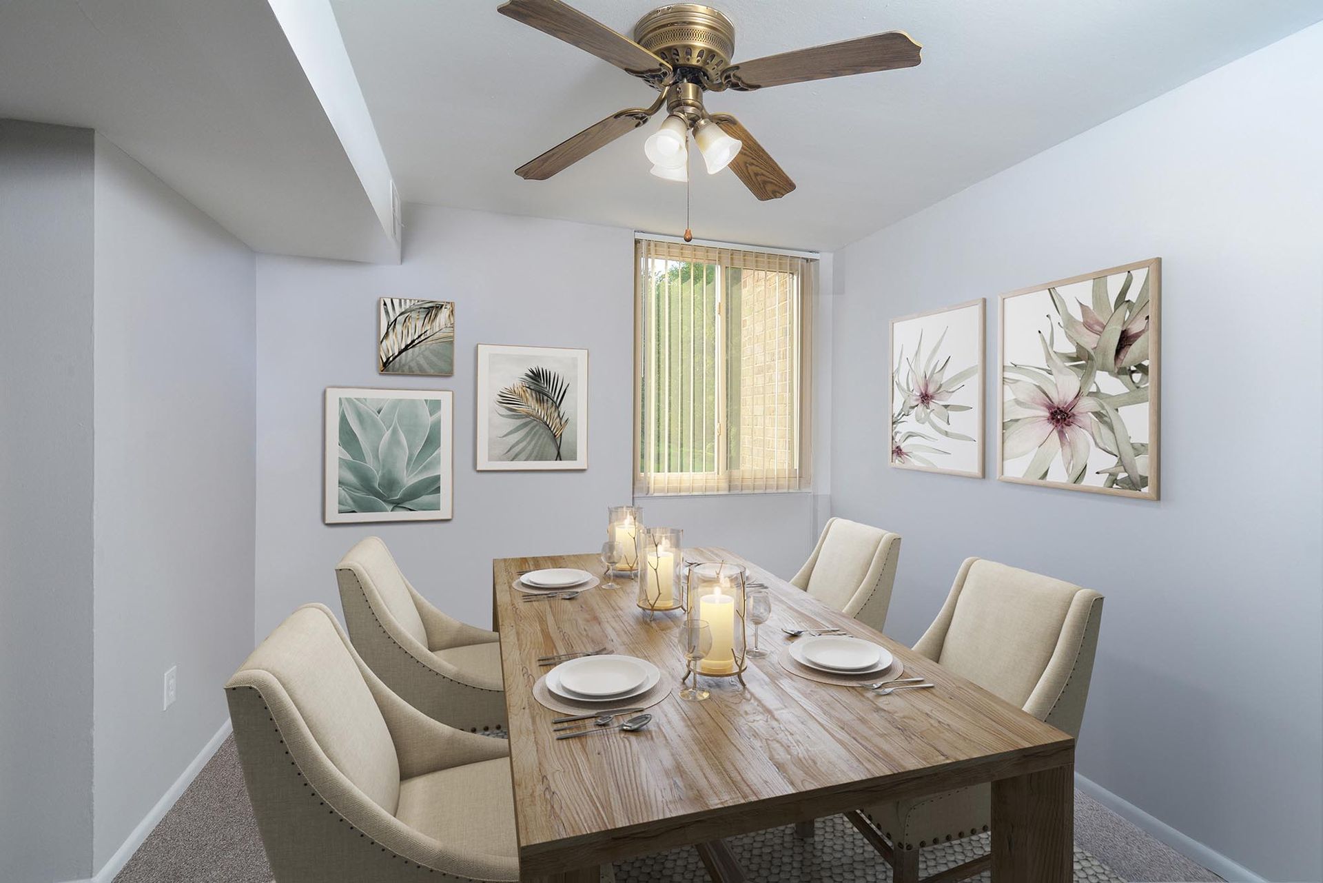 Dining room with wooden table, beige chairs, artwork, and a ceiling fan at Glenmont Station in Silver Spring, MD.