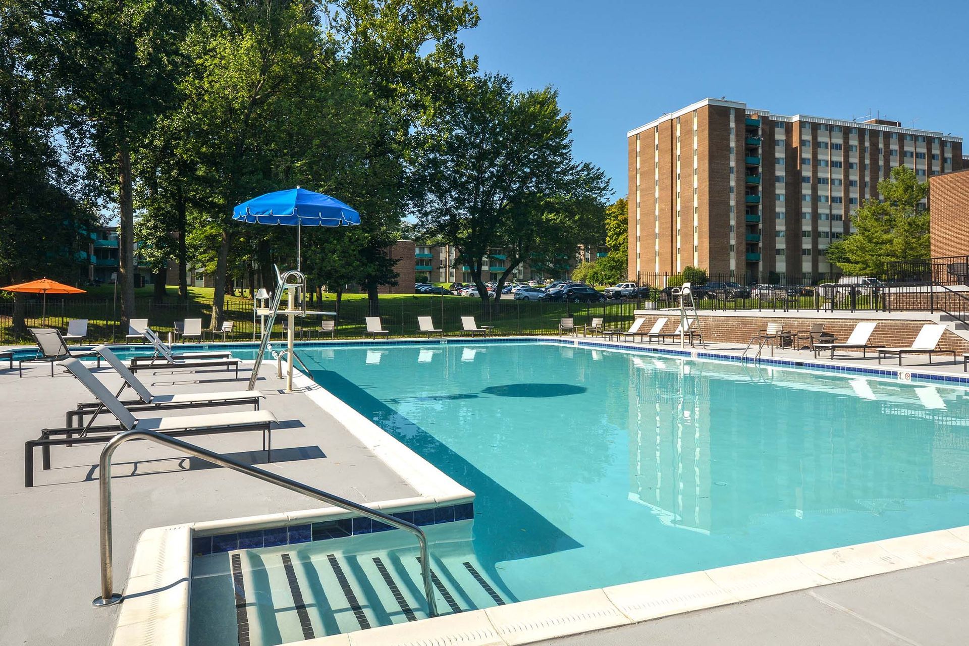 Pool with lounge chairs and lifeguard stand, building in background at Glenmont Station in Silver Spring, MD.