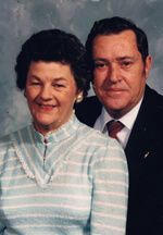Couple posing for a portrait; woman in striped sweater, man in suit.